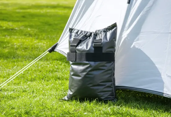 Black vinyl weight bag strapped to the leg of a white pop-up canopy tent