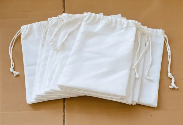 Flat folded empty white polypropylene sandbags with tie strings